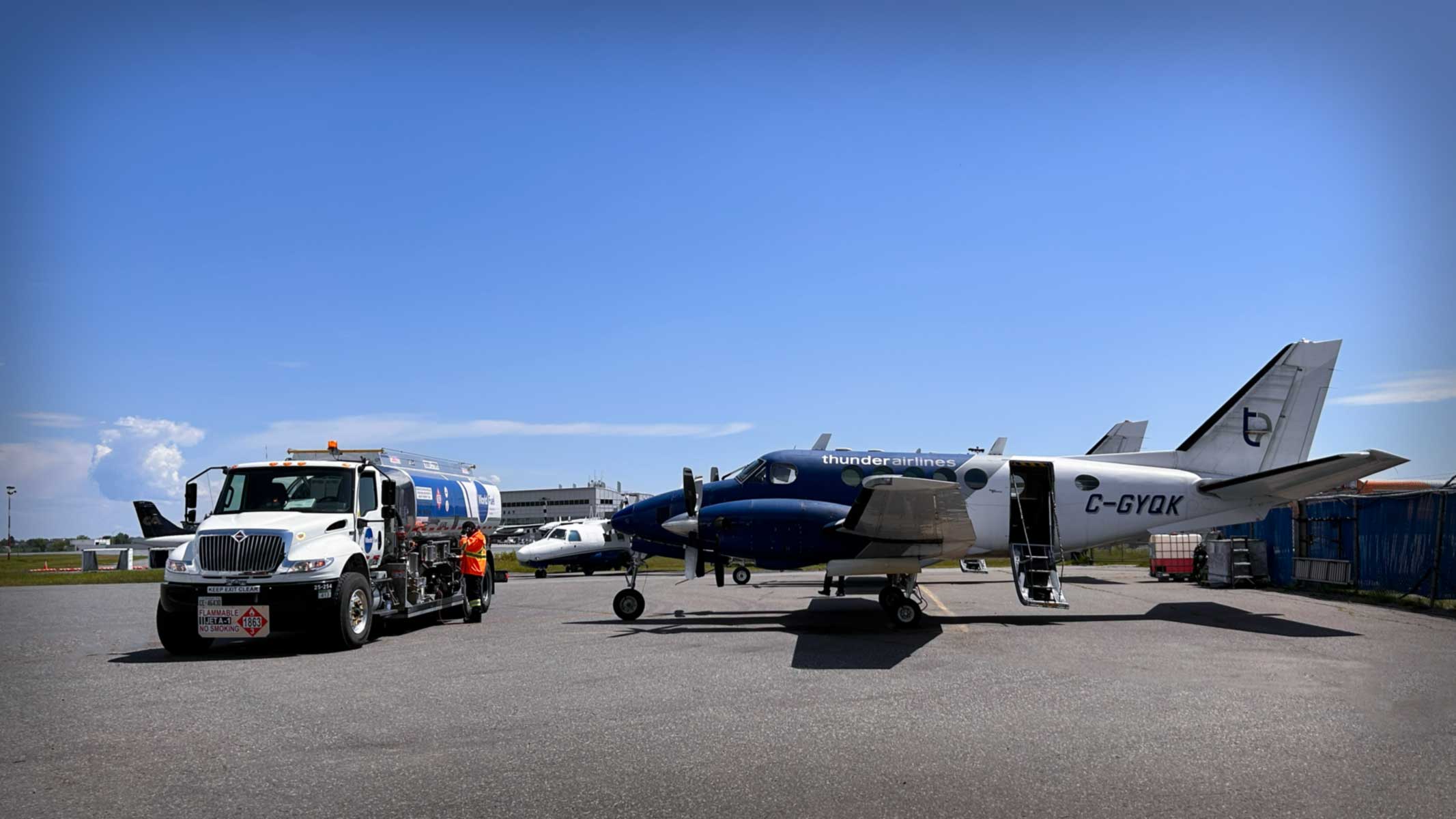 A small blue plane next to a fuel truck.